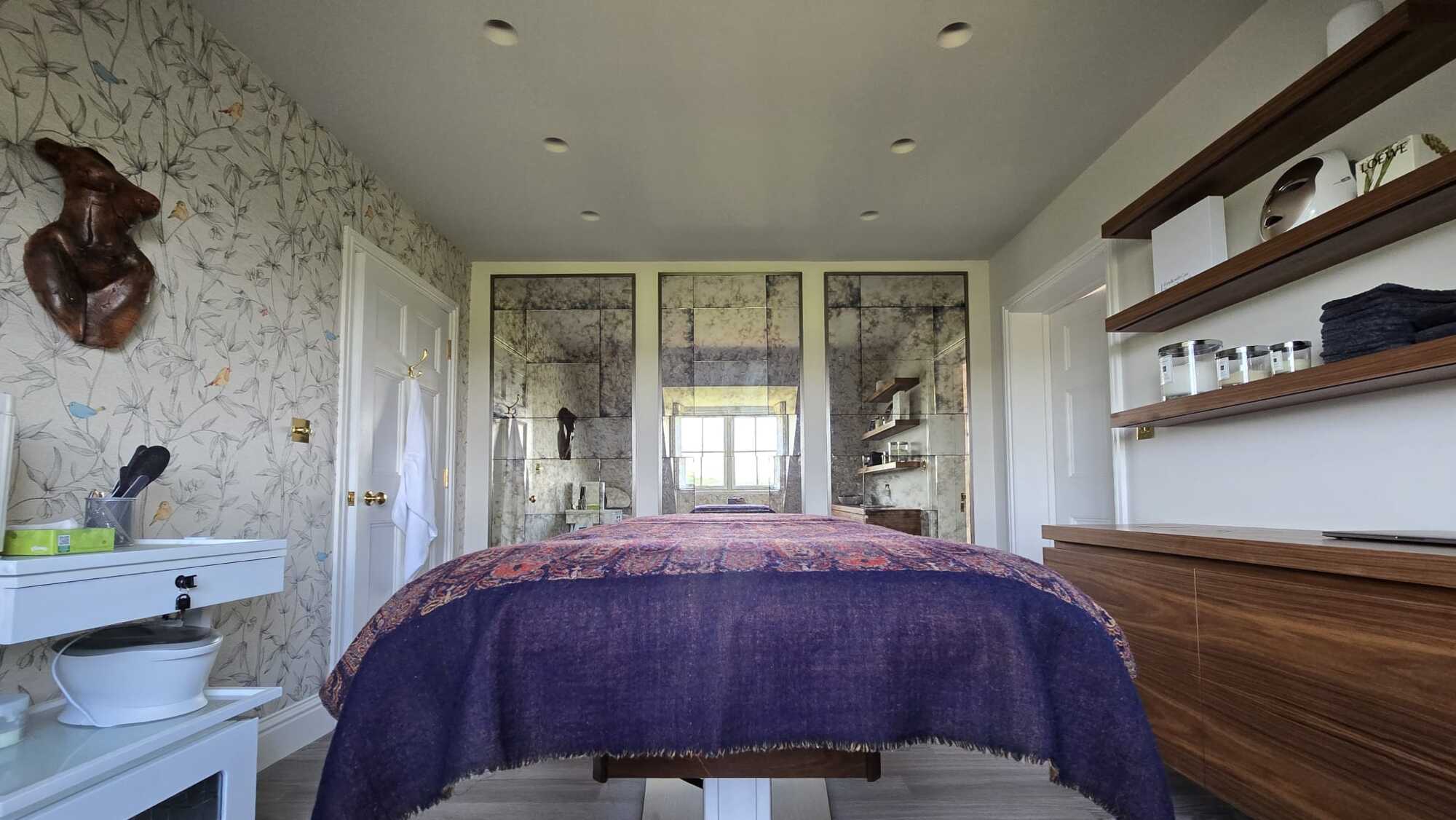 Spa treatment room with antiqued mercury-mirror back wall and concealed Sonance speakers in the joinery line