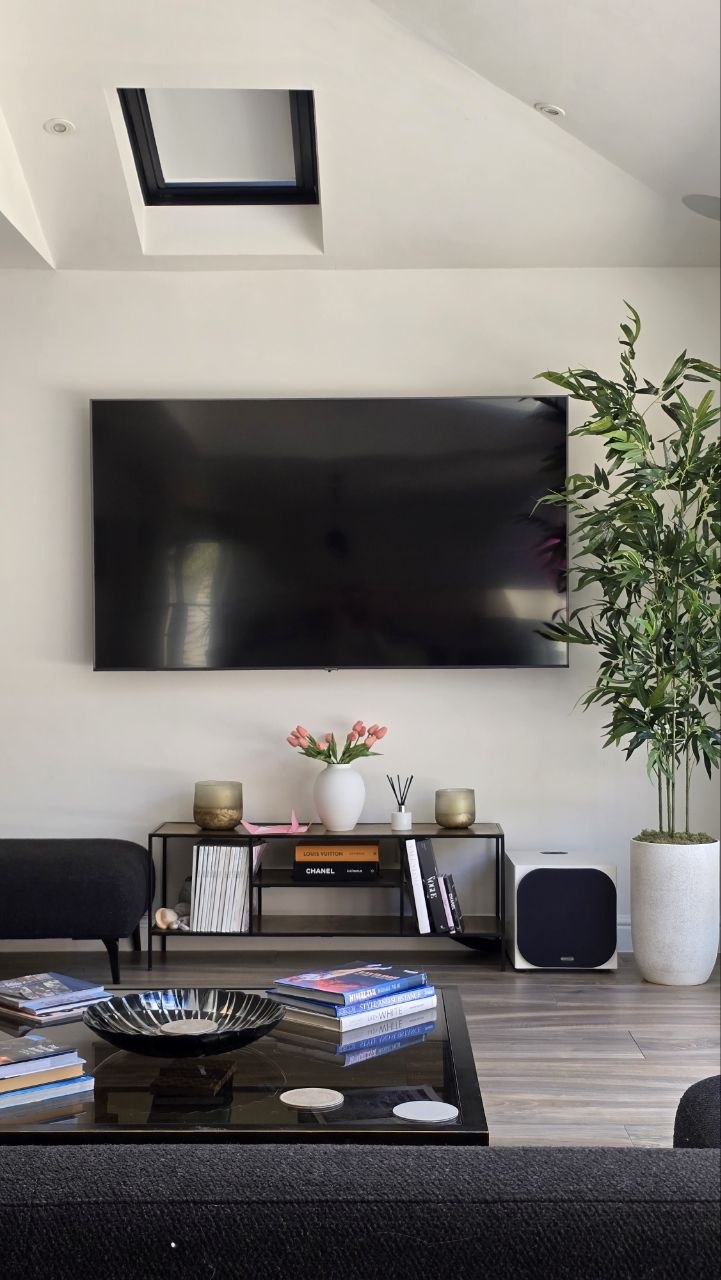 Wall-mounted TV with a compact Monitor Audio subwoofer and hidden in-ceiling surround sound