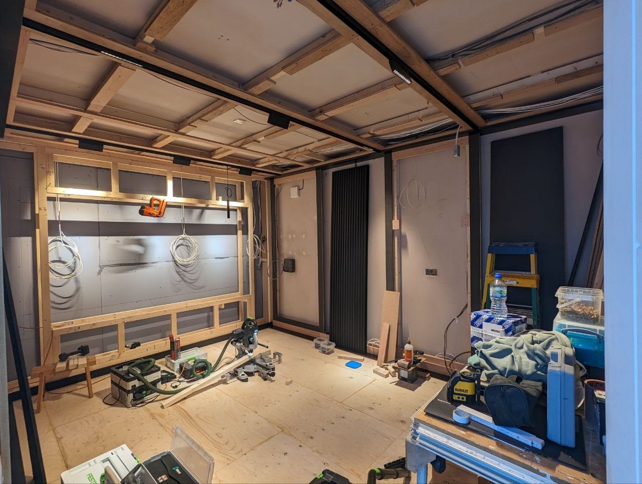 Home cinema room during first fix with timber acoustic wall framing, ceiling battens and tools on site