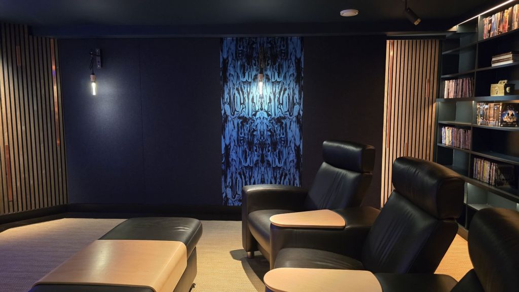Timorous Beasties velvet acoustic panel and wood-slat wall with copper detailing beside a recliner in the Steinway Lyngdorf home cinema near Bath