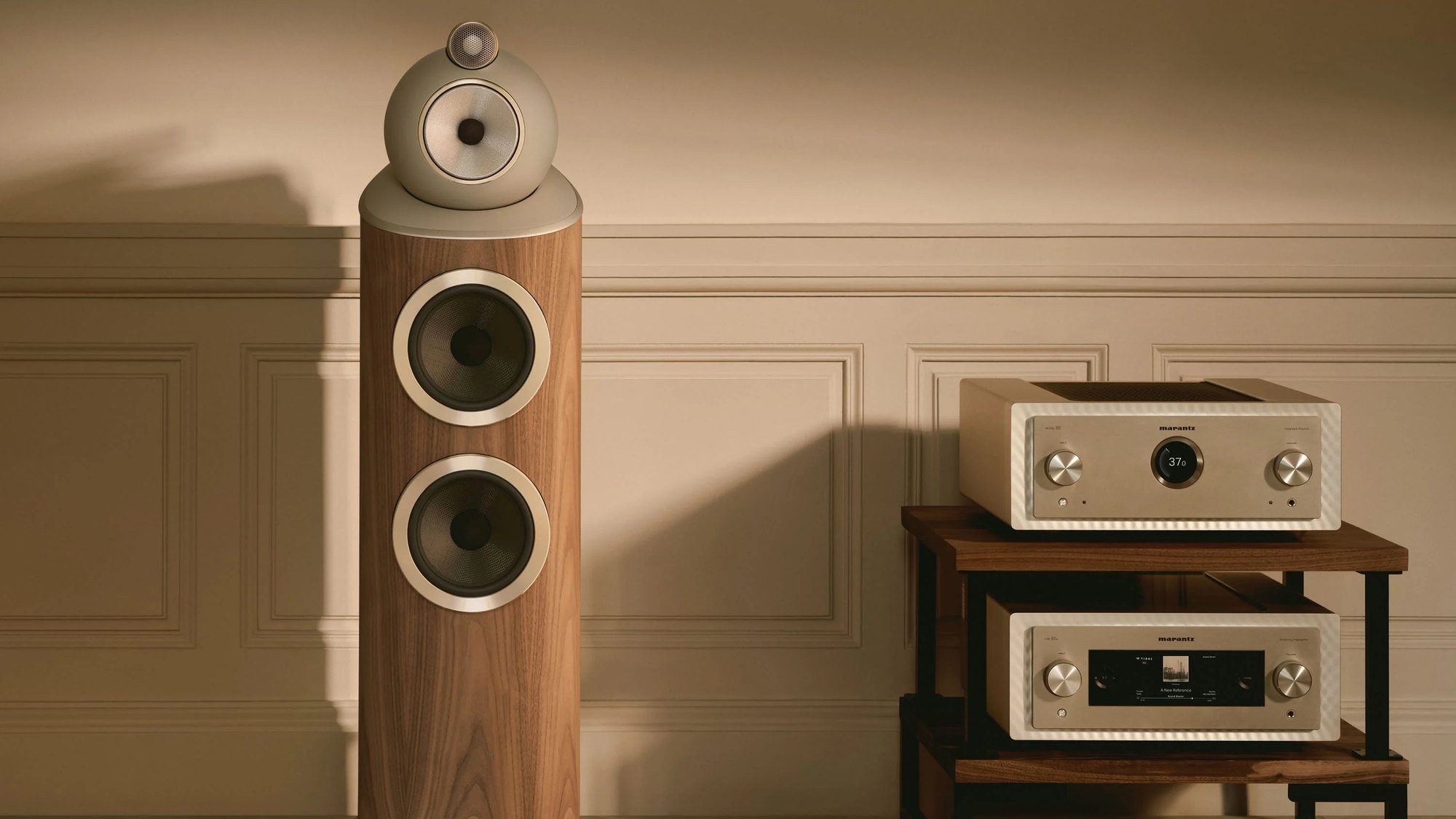 Bowers & Wilkins 803 D5 in a light walnut finish beside a rack of electronics