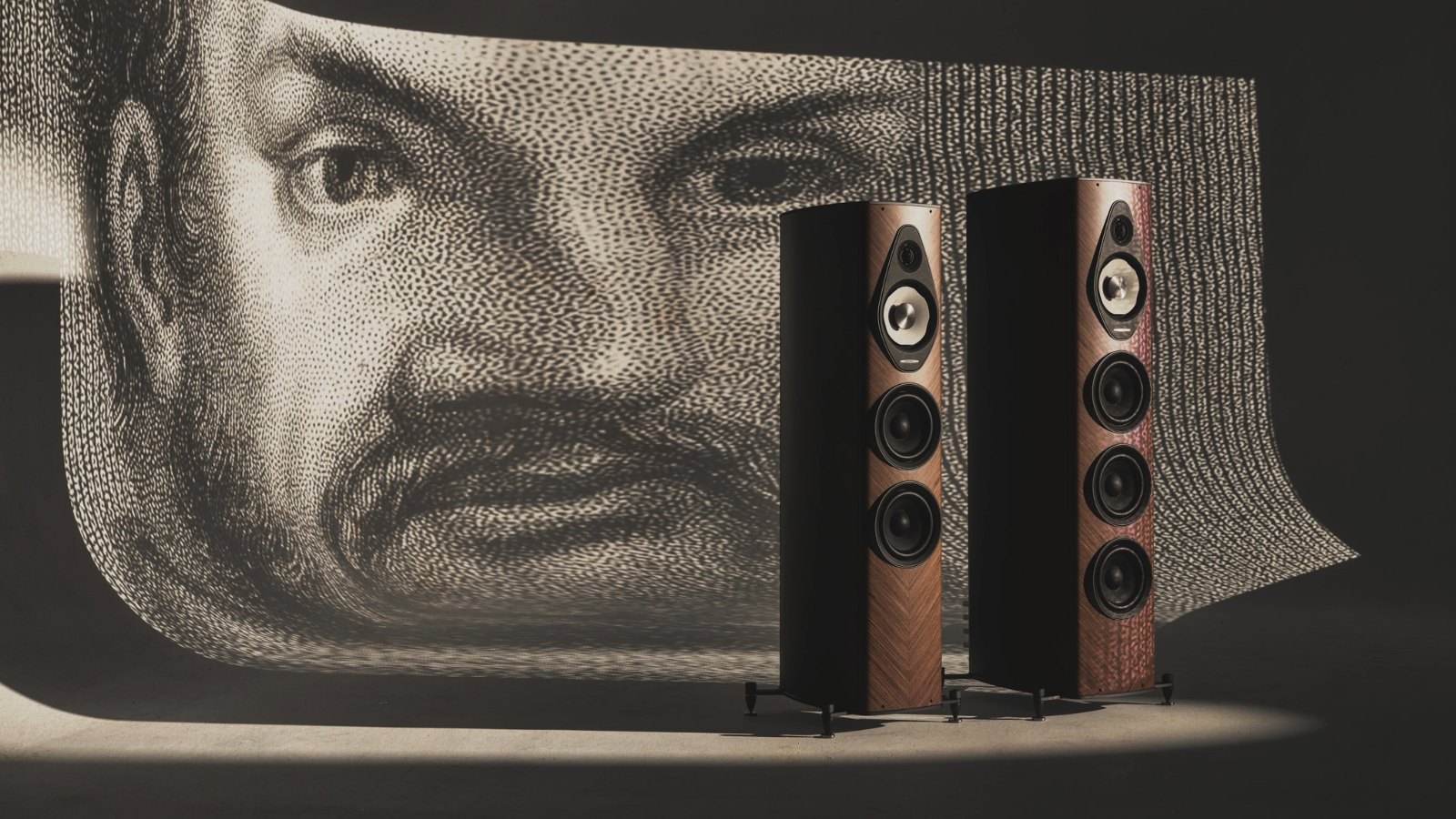 A pair of Sonus Faber Olympica III speakers in front of a large printed portrait